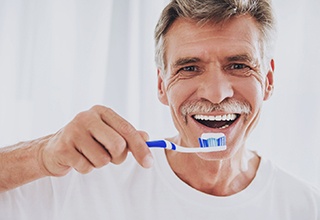 Senior man smiling while brushing his teeth