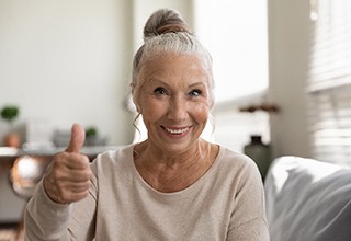 woman smiling while giving thumbs up 