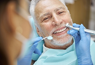 a person smiling while getting their teeth cleaned