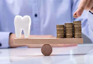 Person placing coins on a teeterboard with a model tooth