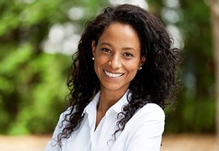 smiling woman with dental implants in Owasso wearing a white button-up shirt 