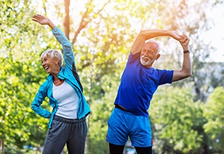 couple stretching outside while wearing exercise clothes 