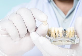 Owasso implant dentist holding dental implant restoration 