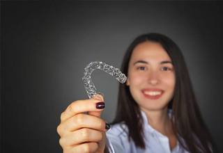 Woman holding clear plastic aligner