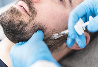 Man receiving dermal filler injection in his jaw
