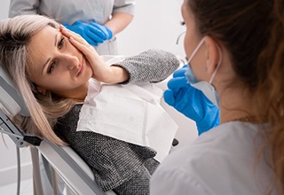 Lady with jaw pain looks to dentist