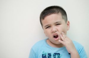 child frowning holding jaw in pain