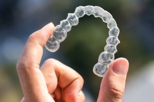 Someone holding up an aligner tray