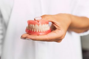 dentist holding set of full dentures in Owasso 