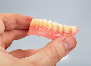 a closeup of a patient holding their dentures