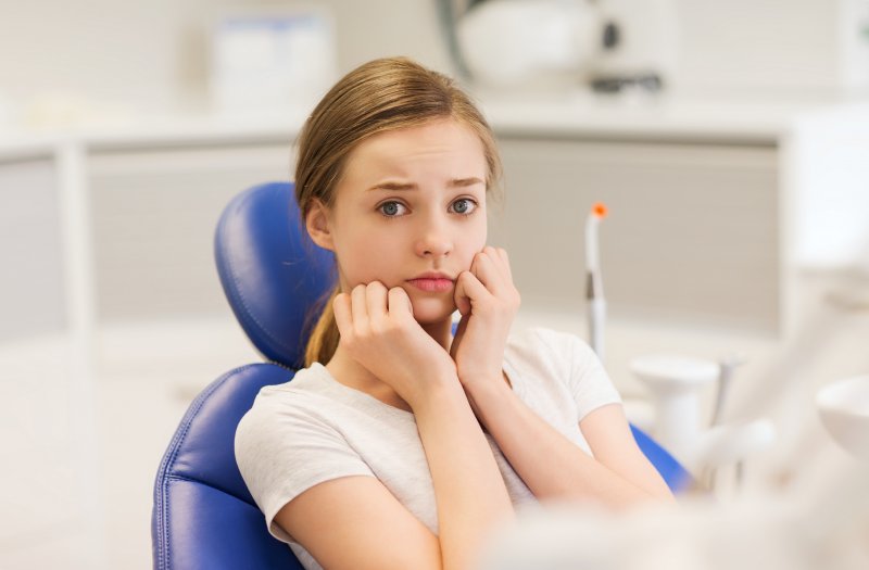 A woman looking nervous in the dentist’s chair before her dental implant surgery