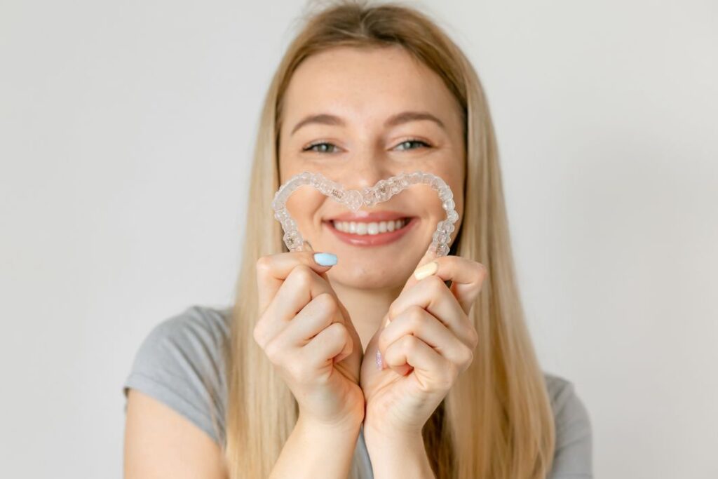 A woman holding a set of Invisalign aligners
