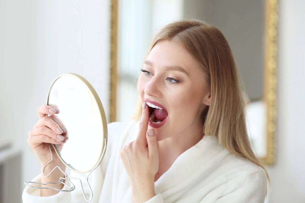 : A woman looking at her teeth in the mirror